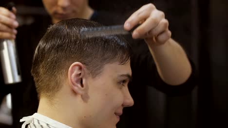 Estilista-profesional-peines-el-cabello-del-hombre-y-la-sprinles-con-agua