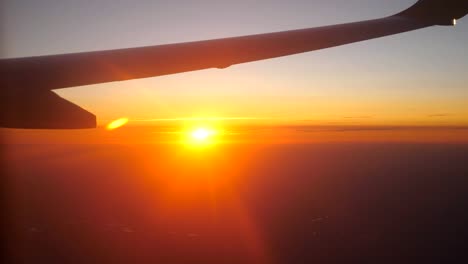 View-from-airplane-window-to-beautiful-sunrise-or-sunset.-Wing-of-plane-and-cloud-in-sky.-Concept-of-travel-or-tourism.-Close-up-Side-view