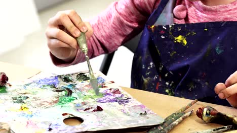 Recorta-la-foto-de-una-chica-apretando-la-pintura-de-un-tubo-a-una-paleta