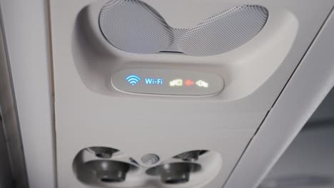 Panel-über-die-Köpfe-der-Passagiere-in-einem-Flugzeug-oder-Bus.-Lüftung-und-Wi-Fi-Abzeichen