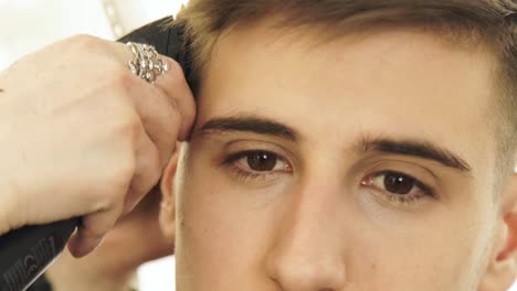 Face-handsome-man-during-haircutting-with-electric-shaver-in-barber-shop.-Close-up-cutting-hair-with-hair-machine.-Man-hairdressing-with-electric-trimmer