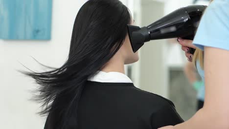 hair-care,-barber-with-hair-dryer-in-hands-blowing-warm-air-on-client-head-at-beauty-Studio