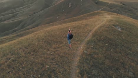 Man-standing-on-top-of-a-mountain-with-raised-hands