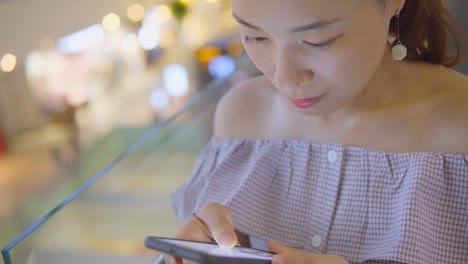 Joven-mujer-de-uso-del-teléfono-móvil-en-el-centro-comercial