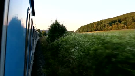 que-se-inclina-por-ventana-de-tren,-en-el-bonito-campo-en-frente