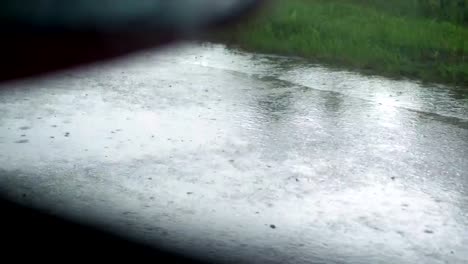 Blick-aus-dem-Autofenster.-Nahaufnahme,-am-Straßenrand,-am-Straßenrand,-in-der-Regen.,-während-das-Auto-in-Bewegung-ist.-Blick-aus-dem-Auto-auf-einer-nassen-Straße