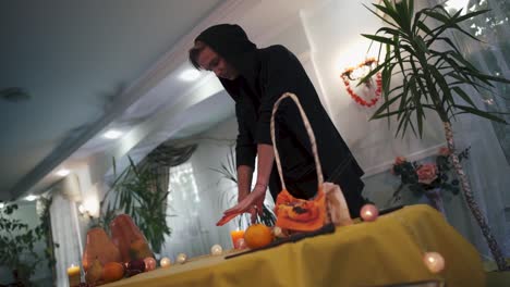 Halloween.-Zauberer-in-der-schwarzen-Haube-neben-dem-Tisch