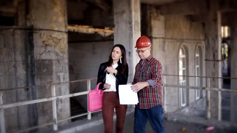 Female-Architect-and-foreman-on-the-site-of-construction-or-restoration,-discuss-the-construction-process-at-the-facility.