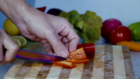 Chef-is-cutting-vegetables-in-the-kitchen,-slicing-sweet-red-bell-pepper