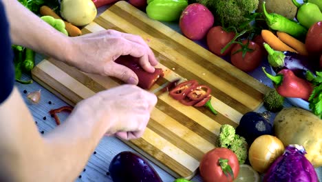 Man-is-cutting-vegetables-in-the-kitchen,-slicing-red-bell-pepper