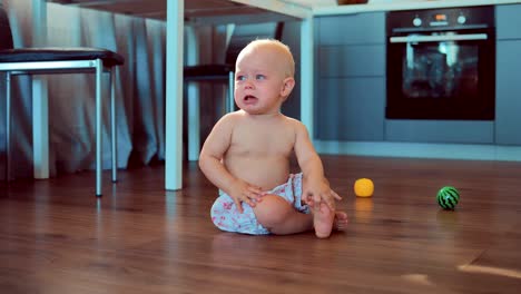 Small-child-is-sitting-on-the-floor-and-crying.-Baby-is-upset-and-look-somewhere