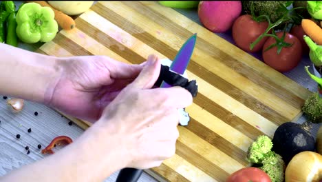 Man-is-cutting-vegetables-in-the-kitchen,-slicing-tomato-in-slow-motion