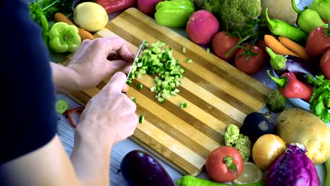 Man-is-cutting-vegetables-in-the-kitchen,-slicing-tomato-in-slow-motion