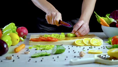 Man-is-cutting-vegetables-in-the-kitchen,-slicing-green-bell-pepper