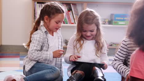 Two-elementary-school-schoolgirls-sharing-tablet-in-class