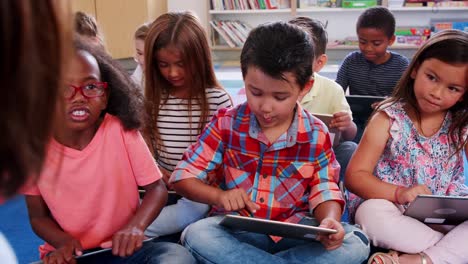 Lehrer-und-Schüler-sitzen-auf-dem-Boden-mit-Tabletten-in-der-Klasse