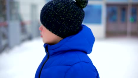 Boy-teenager-in-blue-down-jacket-lost-in-the-city.-He's-at-the-train-station,-looks-around.