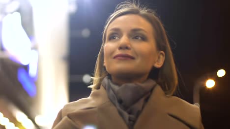 Smiling-beautiful-female-enjoying-evening-promenade-in-illuminated-megalopolis