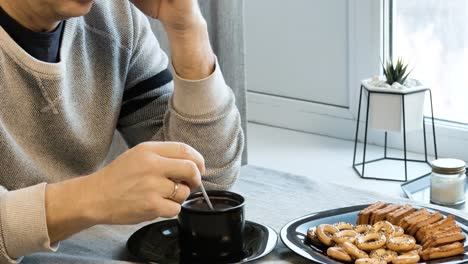 Man-mischt-sich-mit-Kaffee-in-der-Tasse.-Er-ist-sehr-traurig.-In-seiner-Küche-zu-Hause.-Er-macht-sich-Sorgen-wegen-seiner-Probleme.