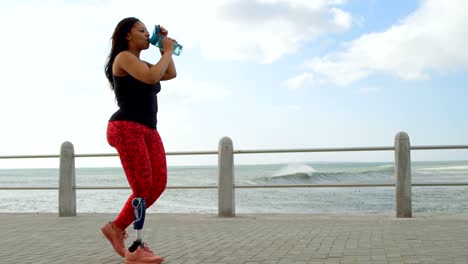 Side-view-of-disabled-woman-drinking-water-on-promenade-4k