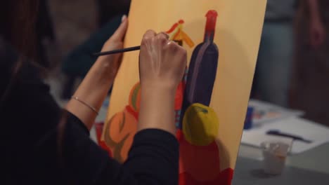 Young-woman-artist-is-painting-picture-on-canvas-in-art-studio