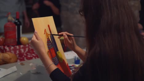 Young-woman-artist-is-painting-picture-on-canvas-in-art-studio