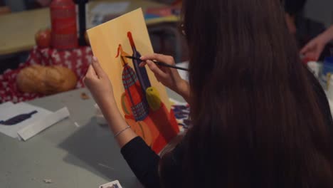 Young-woman-artist-is-painting-picture-on-canvas-in-art-studio