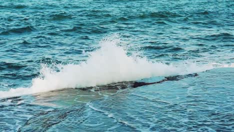 Las-olas-color-turquesa-es-chocar-con-rocas-de-piedra-cerca-de-la-orilla-y-convirtiendo-en-miles-de-gotas-de-agua.