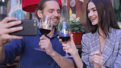 Happy-Couple-With-Wine-Taking-Photos-On-Phone-At-Restaurant