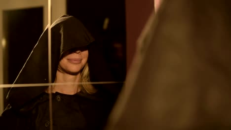 Close-up-of-a-girl-magician-in-front-of-a-mirror-puts-on-the-hood-of-his-suit-time-after-time.-Live-camera.