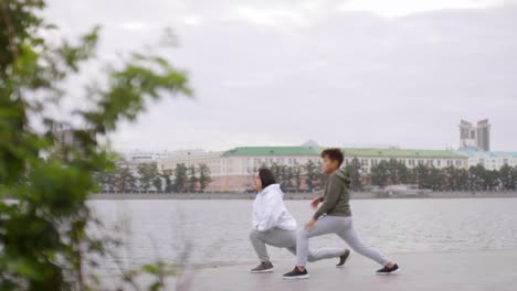 Asiatische-Mutter-und-Sohn-tun-vorwärts-Lunges-auf-Urban-Riverside