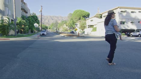 Woman-carrying-her-baby-on-a-carrier-as-she-crosses-a-street