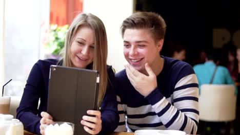 Pareja-atractiva-joven-con-tableta-digital,-mirando-la-pantalla-en-el-café.