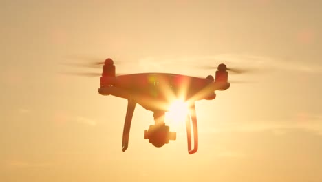 SLOW-MOTION-CLOSE-UP-SILHOUETTE-Filming-Drohne-mit-Kamera-überfliegt-der-aufgehenden-Sonne