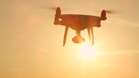 SLOW-MOTION-SILHOUETTE:-Quadrocopter-Drohne-fliegen-in-Richtung-der-Sonne-am-goldenen-Sonnenuntergang