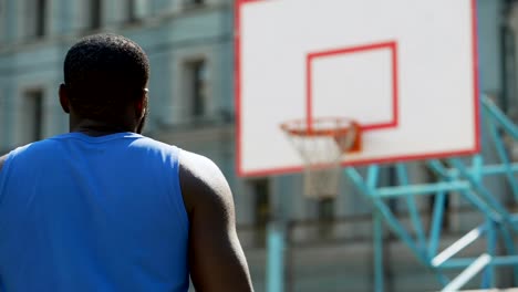 Back-view-of-basketball-player-practicing-free-throws-outdoors,-active-lifestyle