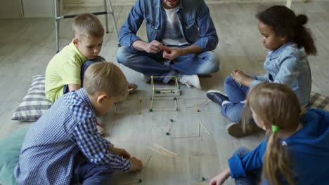 Kids-and-Male-Teacher-Making-Wooden-3D-Shapes