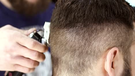 Professional-stylist-makes-hairstyle-with-electric-razor-to-client-in-barbershop