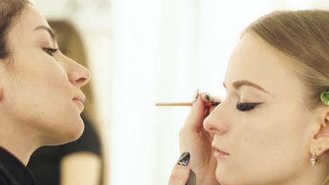 Mujer-maquilladora-utilizando-cepillo-cosméticos-para-maquillaje-ojos-belleza-modelo.-Visagist-haciendo-cara-de-maquillaje-para-la-mujer-hermosa-de-cerca