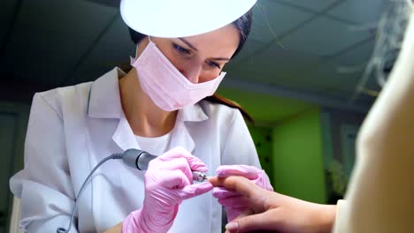 Beautician-careful-and-accurate-removing-cuticles-with-polish-machine