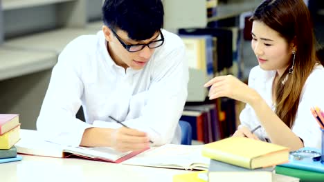 Lassen-Sie-uns-zusammenarbeiten,-um-unsere-Gruppe-Werk-zu-vollenden.-Junge-Studenten-forschen-gemeinsam-in-der-Bibliothek.-Chinesischen-jungen-und-Mädchen.
