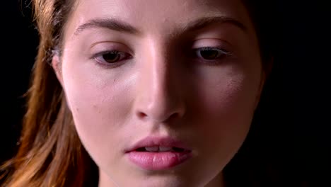 Close-portrait-of-serious-young-woman-looking-at-camera,-isolated-on-black-studio-background,-concerned-and-concentrated