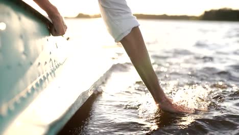 At-sunset,-close-up-the-hand-of-a-girl-moving-through-the-water