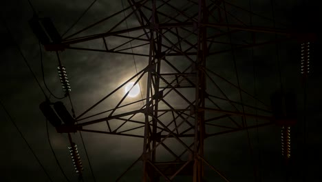 the-moon-in-the-cloudy-sky,-visible-through-the-power-line-support,-time-lapse.