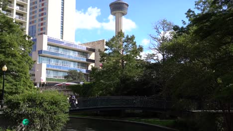 San-Antonio-River-Walk-Boote-Verkehr-Vorzeichenänderung-Gebäude-mit-Turm-im-Hintergrund-Zeitraffer