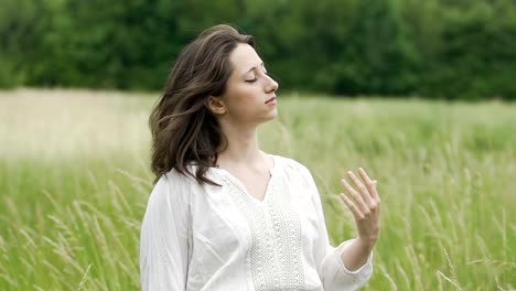 Frau-mit-Augen-geschlossen-stehen-im-Feld-Gefühl-Wind-und-Einssein-mit-der-Natur