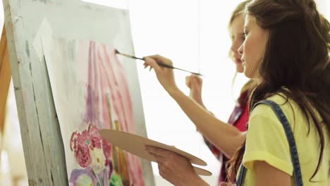 chicas-estudiantes-con-la-pintura-de-caballete-en-la-escuela-de-arte