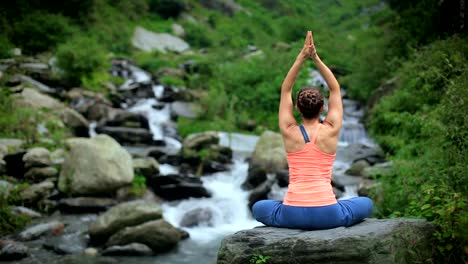 Woman-meditating-at-tropical-waterfall