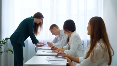 Kaukasische-junge-Lehrerin-Chek-und-Kontrolle-College-Studenten-Kenntnisse-und-Fertigkeiten-im-Klassenzimmer