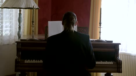 Long-hair-musician-reading-music-sheet-and-playing-piano